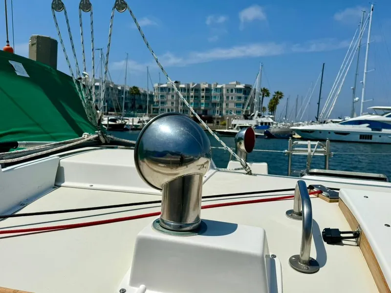 Slide: The Image of Pearson Ketch 1982 sailboat deck with marina view, featuring chrome fittings and green cover. - 5