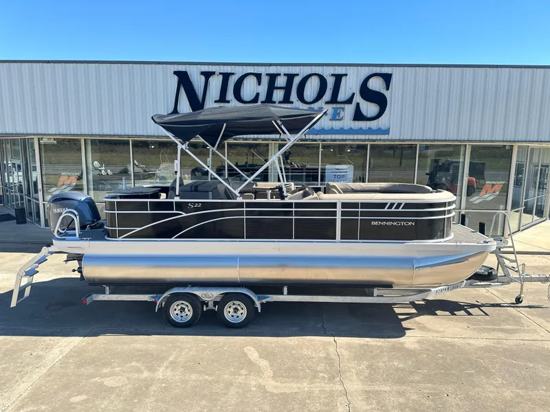 Slide: The Image of 2025 Bennington 22 SXS APG pontoon boat on trailer outside Nichols store. - 1