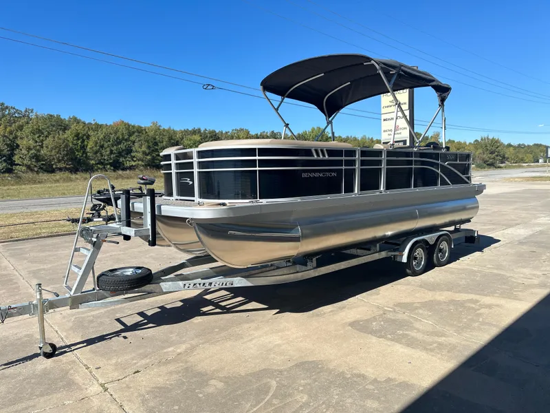 Slide: The Image of 2025 Bennington 22 SXS APG pontoon boat on trailer, parked outdoors. - 2