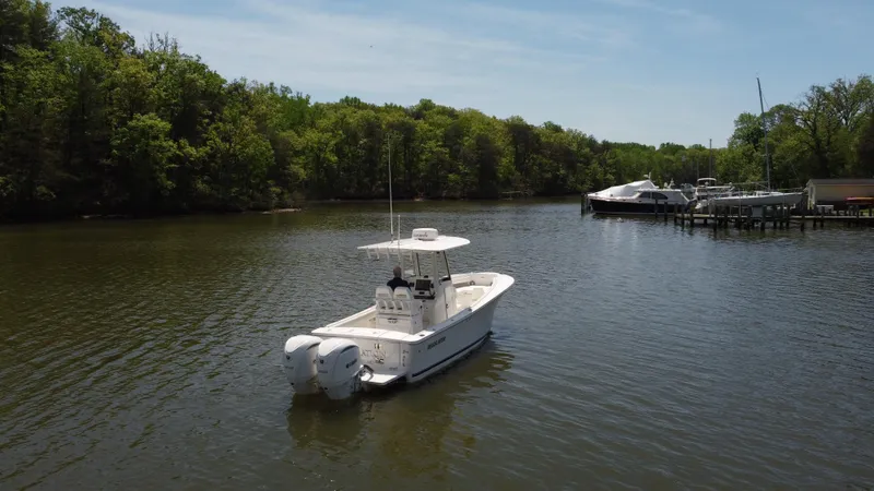 Slide: The Image of 2022 Regulator 25FS boat on a calm river near a dock with trees. - 11
