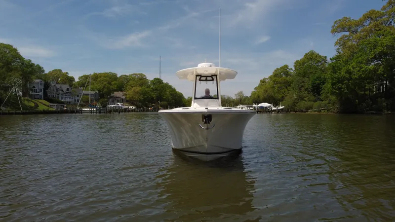 Slide: The Image of 2022 Regulator 25FS boat on calm water, surrounded by lush greenery and waterfront homes. - 2