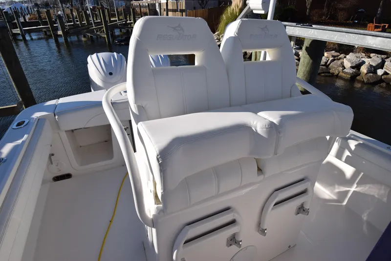 Slide: The Image of 2022 Regulator 25FS boat with white cushioned seating, docked by the water. - 31
