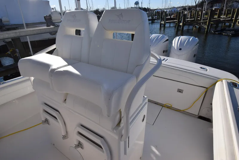 Slide: The Image of 2022 Regulator 25FS boat with white seating and dual outboard motors at a marina. - 32