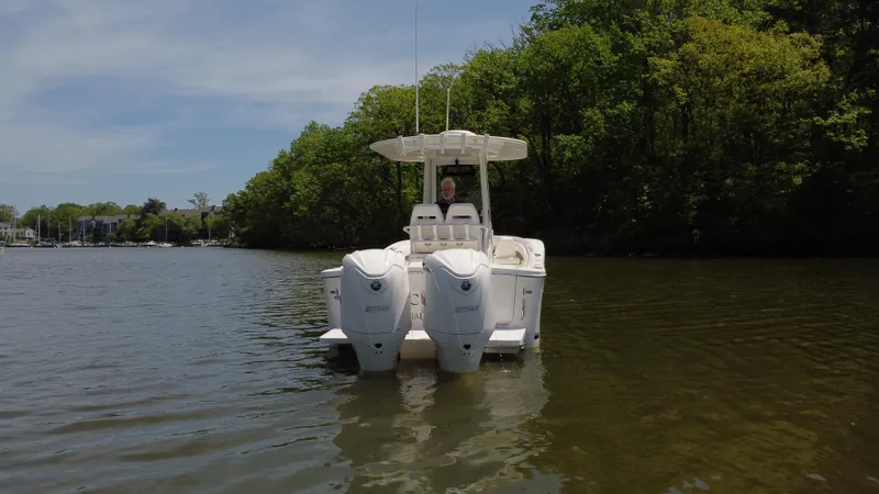 Slide: The Image of 2022 Regulator 25FS boat on calm water, surrounded by lush greenery. - 4