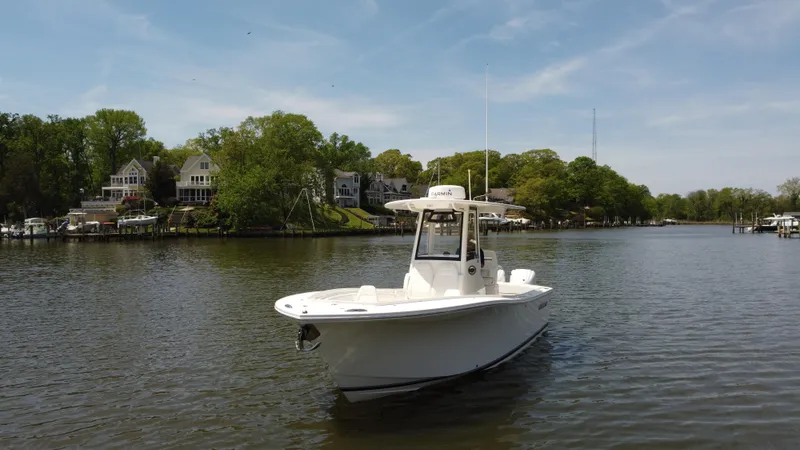 Slide: The Image of 2022 Regulator 25FS boat on a serene river with houses and trees in the background. - 5