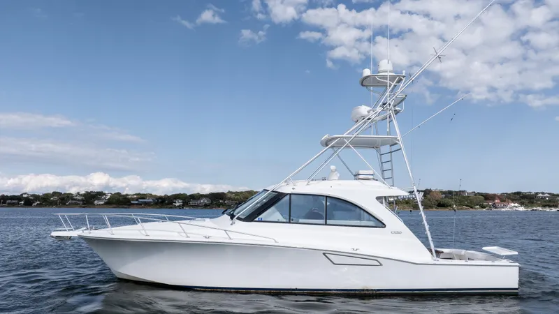Slide: The Image of 2012 Cabo 44 HTX yacht on calm water under a blue sky. - 2