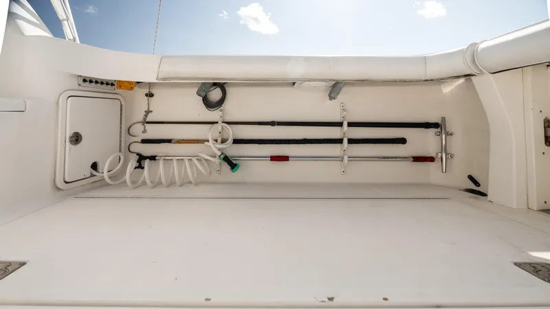 Slide: The Image of Fishing equipment storage on 2012 Cabo 44 HTX boat deck, featuring rods and coiled hose. - 22