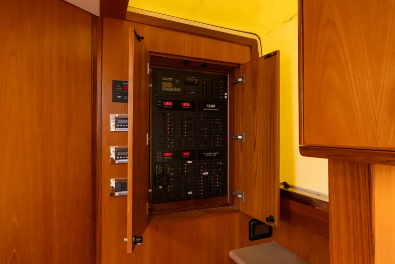 Slide: The Image of Electrical panel inside 2012 Cabo 44 HTX yacht, featuring wooden cabinetry and control switches. - 43