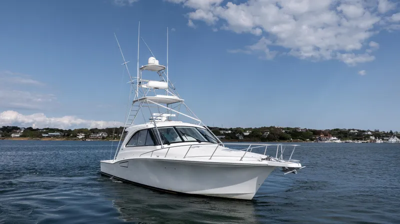 Slide: The Image of 2012 Cabo 44 HTX yacht on calm water under a partly cloudy sky. - 7