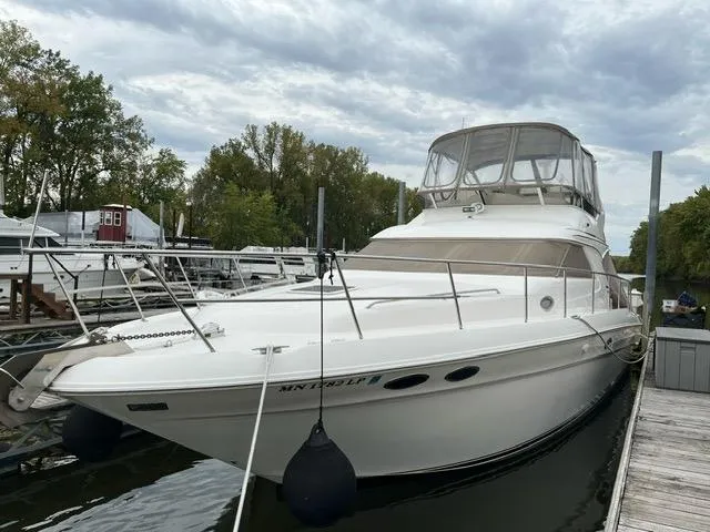 Slide: The Image of 1997 Sea Ray 400 Sedan Bridge yacht docked at marina under cloudy sky. - 0