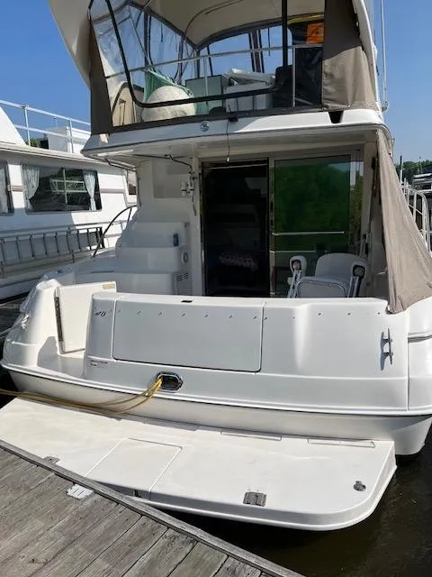 Slide: The Image of 1997 Sea Ray 400 Sedan Bridge yacht docked, rear view with canopy and seating area. - 4