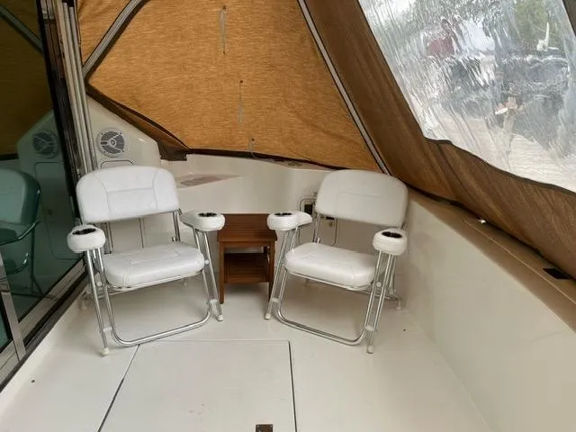 Slide: The Image of 1997 Sea Ray 400 Sedan Bridge interior with two white chairs and brown curtains. - 5