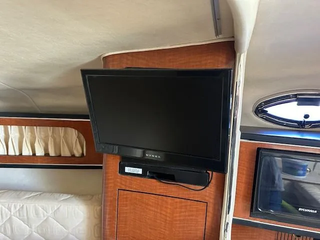 Slide: The Image of Interior of 2003 Sea Ray 280 Sundancer with mounted TV and wood paneling. - 12