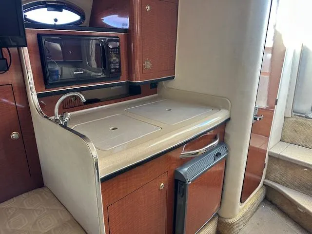 Slide: The Image of 2003 Sea Ray 280 Sundancer cabin kitchen with microwave, sink, and mini fridge. - 13