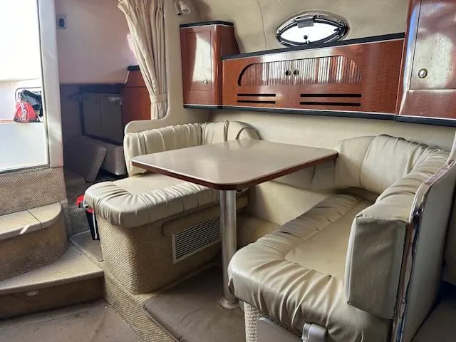 Slide: The Image of 2003 Sea Ray 280 Sundancer cabin with beige seating and wooden accents. - 15