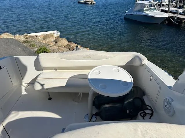 Slide: The Image of 2003 Sea Ray 280 Sundancer boat interior with seating and table, docked by the water. - 6