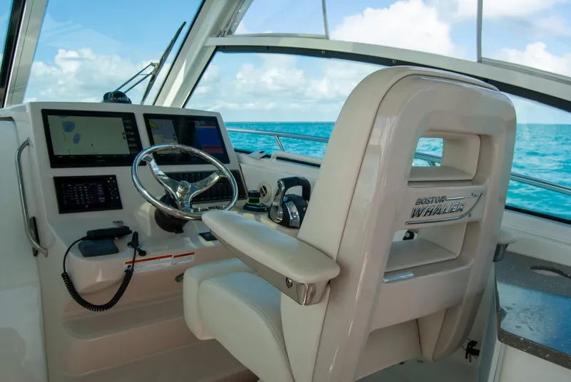 Slide: The Image of 2021 Boston Whaler 345 Conquest helm with steering wheel and navigation screens, ocean view. - 2