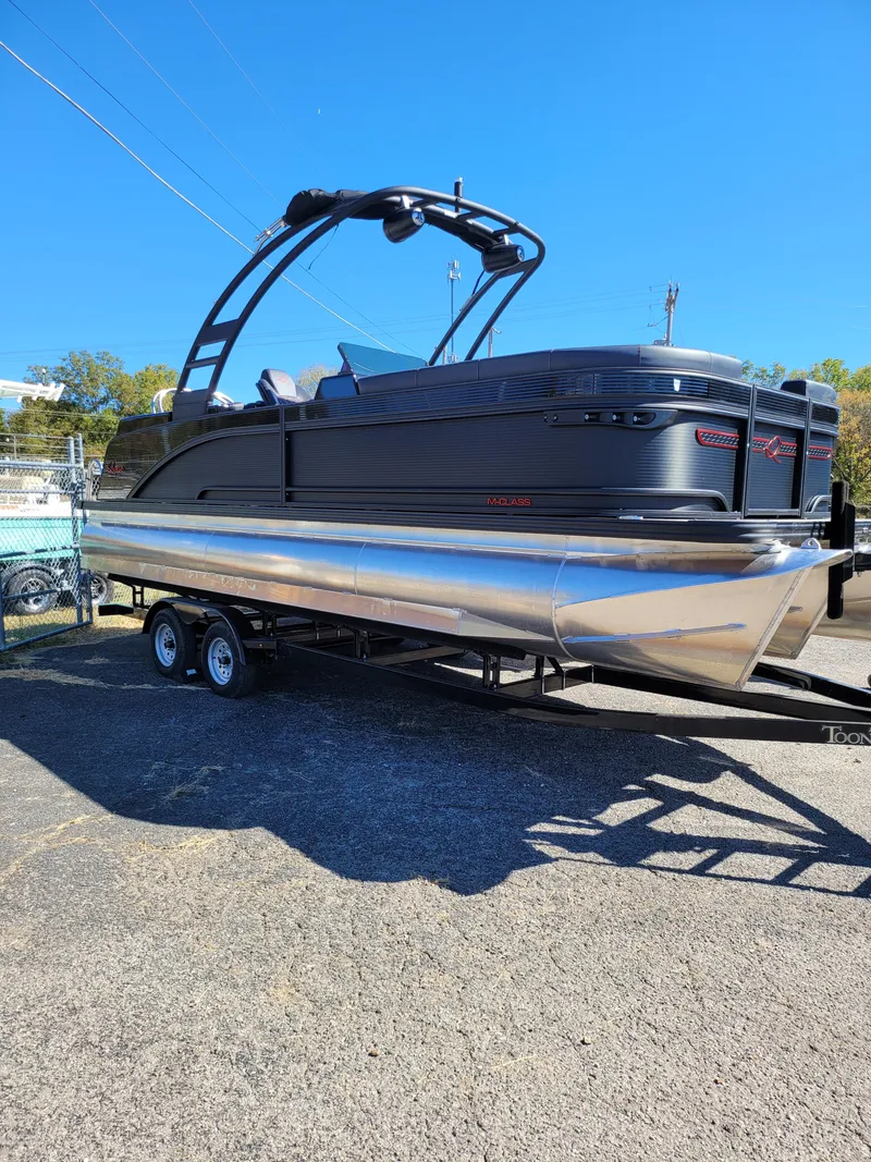 Slide: The Image of 2025 Quest M-22RLS LIMITED pontoon boat on trailer, sleek design, black and silver finish. - 0