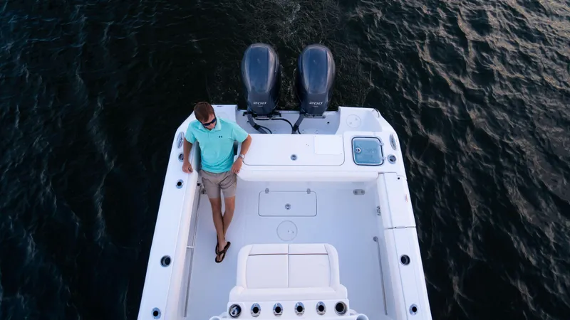 Slide: The Image of 2025 Sea Hunt Gamefish 27 Coffin Box boat on water, man standing on deck. - 29