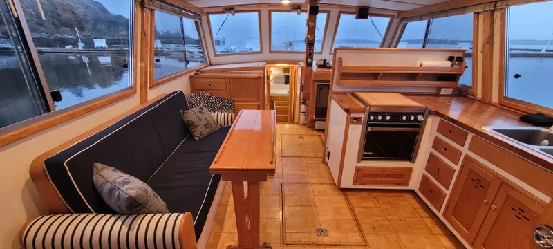 Slide: The Image of 1989 Duffy Wilbur 42 Flybridge Cruiser interior with cozy seating, wooden cabinetry, and scenic marina view. - 8