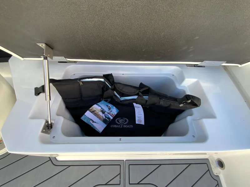 Slide: The Image of 2025 Cobalt R6 Outboard storage compartment with boating gear and brochure. - 26