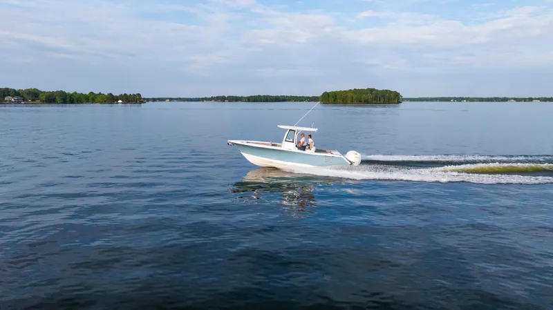 Slide: The Image of 2025 Sea Hunt Gamefish 27 cruising on a serene lake with lush islands. - 10