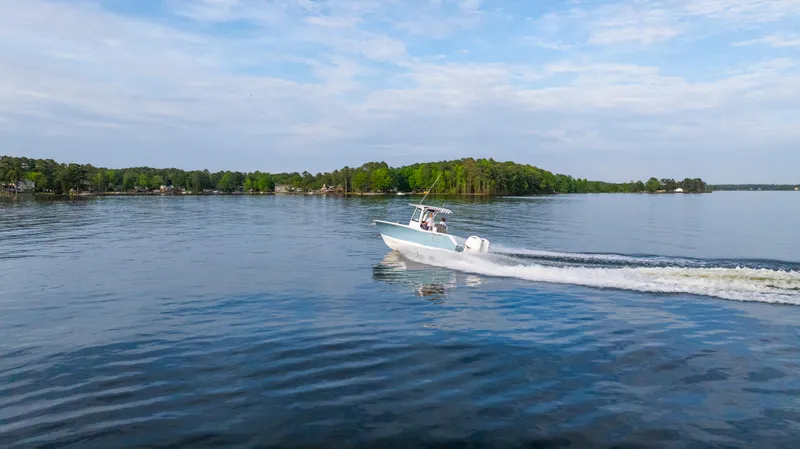 Slide: The Image of 2025 Sea Hunt Gamefish 27 cruising on a serene lake under a blue sky. - 13