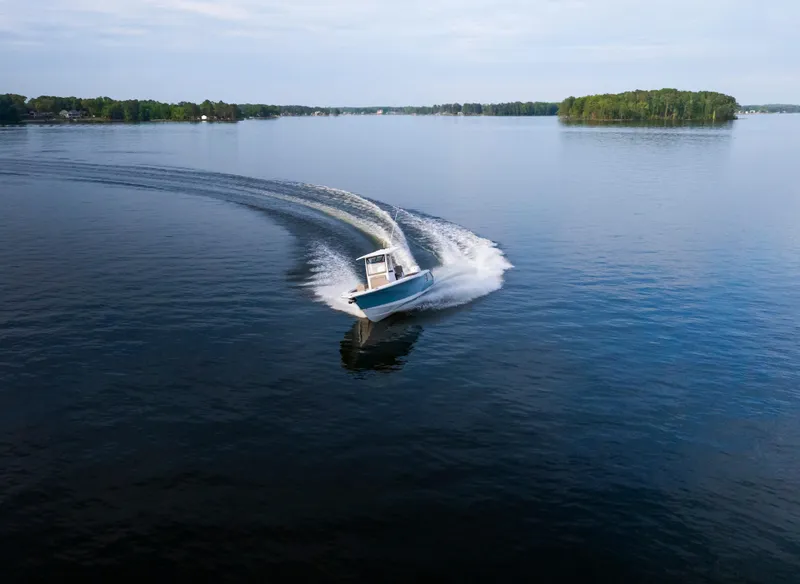 Slide: The Image of 2025 Sea Hunt Gamefish 27 cruising on a serene lake with lush islands. - 9
