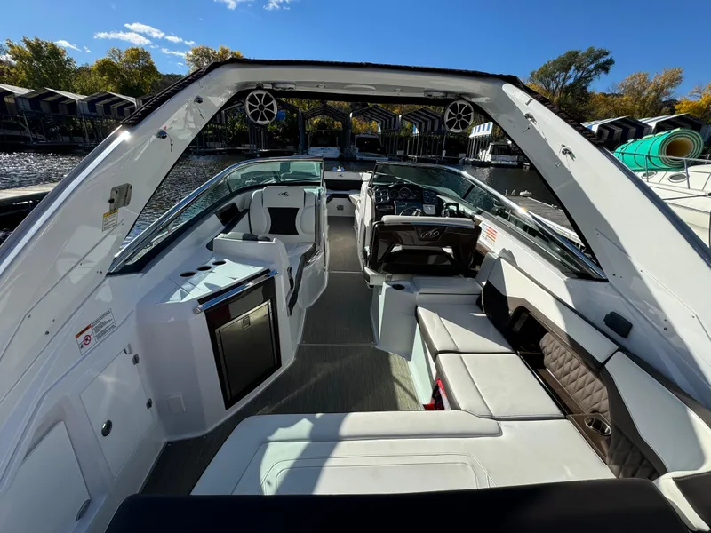 Slide: The Image of 2018 Monterey 328 Super Sport boat interior with seating and control panel, docked by the water. - 10
