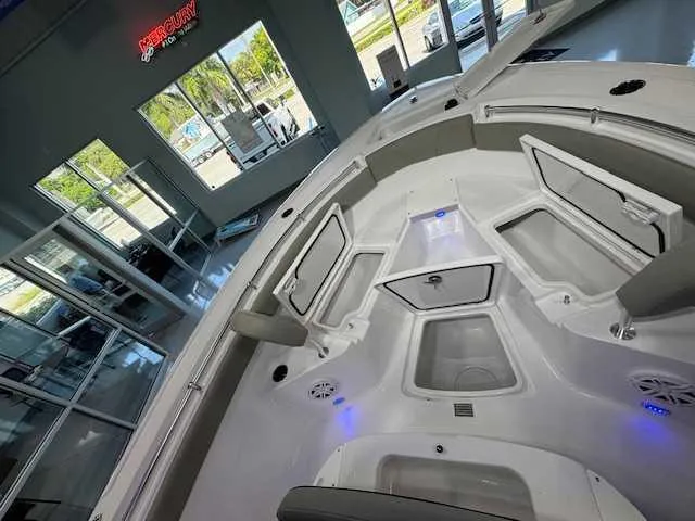Slide: The Image of 2025 Sportsman Open 212 boat interior with storage compartments and seating in showroom. - 20