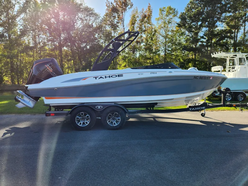 The Image of 2021 Tahoe 210 S boat on trailer, parked outdoors with trees in the background. - 0
