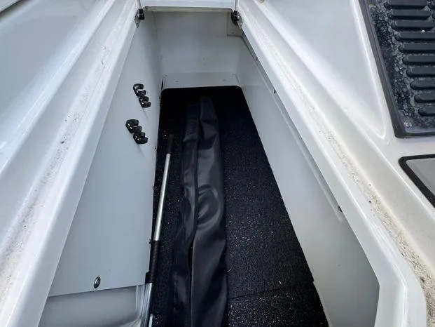 Slide: The Image of 2023 Cobalt R8 Outboard storage compartment with black cover and accessories. - 49