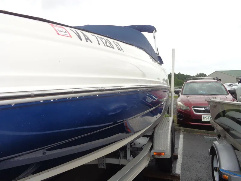 Slide: The Image of 2007 Sea Ray 200 Sundeck boat on trailer, parked beside a red car. - 19