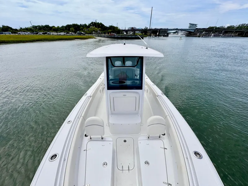 Slide: The Image of 2024 Sea Hunt Ultra 265 SE boat on calm water, showcasing sleek design and spacious deck. - 7