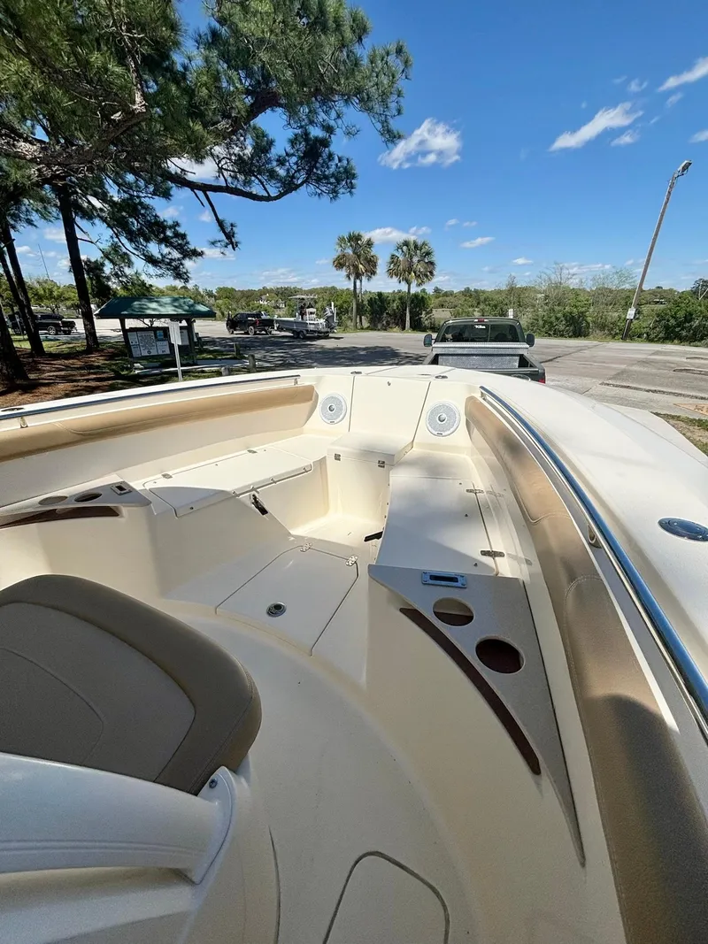Slide: The Image of 2019 Scout 255 LXF boat interior with seating and cup holders, under a clear blue sky. - 7