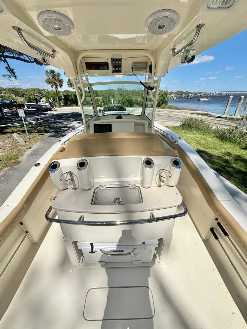 Slide: The Image of 2019 Scout 255 LXF boat interior with console and seating, near scenic waterfront. - 8