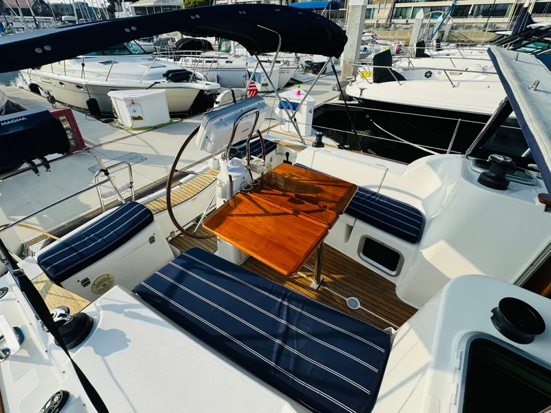 Slide: The Image of 2007 Jeanneau Sun Odyssey 36i sailboat cockpit with seating and wooden table at marina. - 17