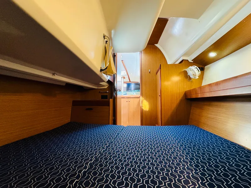 Slide: The Image of Interior cabin of 2007 Jeanneau Sun Odyssey 36i sailboat, featuring wood paneling and blue bedding. - 43