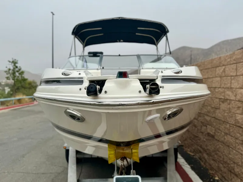 Slide: The Image of 2006 Larson LXi 248 boat on trailer, parked outdoors with scenic background. - 2