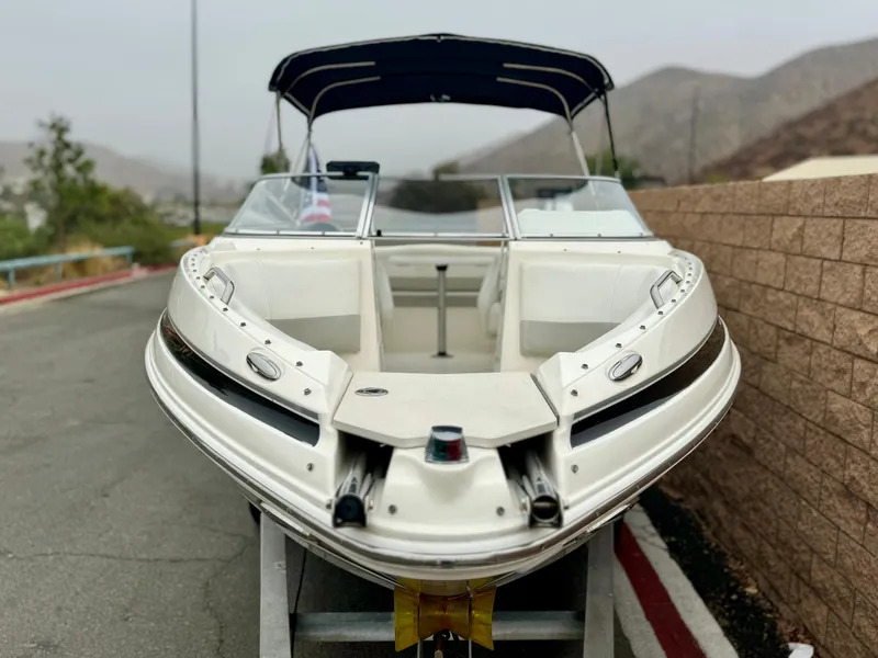 Slide: The Image of 2006 Larson LXi 248 boat on trailer, parked on roadside with scenic background. - 3