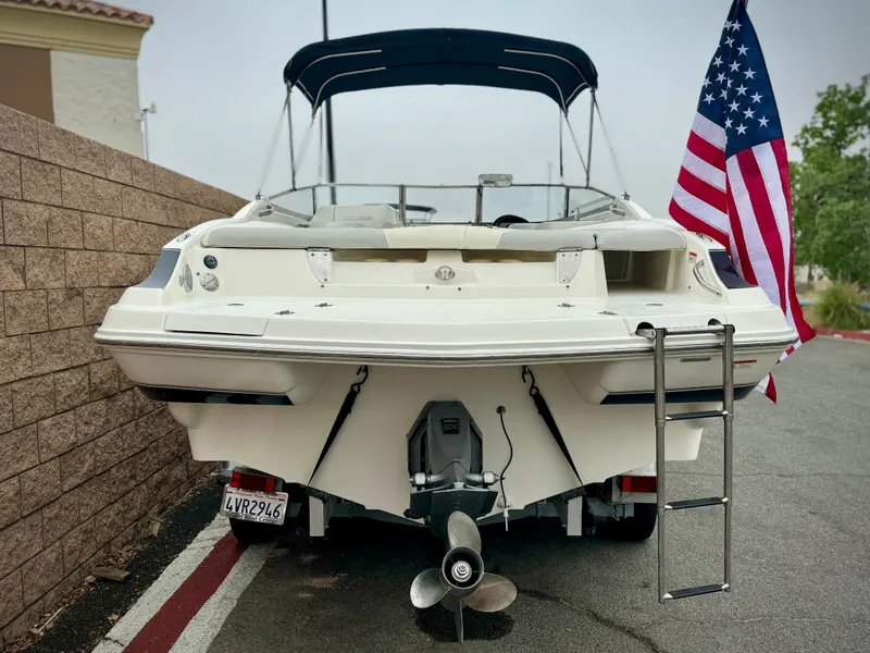 Slide: The Image of 2006 Larson LXi 248 boat on trailer with black canopy, parked outdoors. - 5