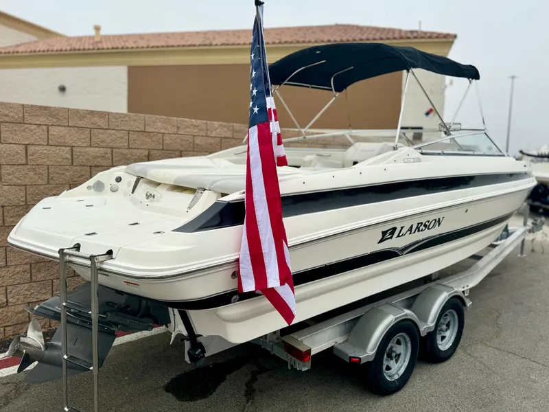 Slide: The Image of 2006 Larson LXi 248 boat with American flag, rear view, parked near brick wall. - 6