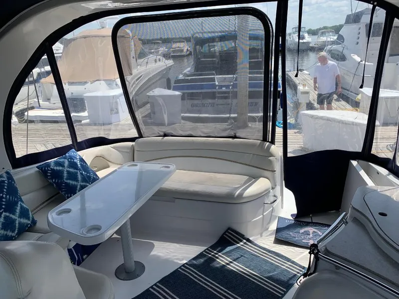Slide: The Image of 2004 Larson Cabrio 370 interior with seating, table, and marina view. - 11