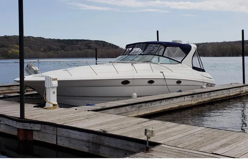 Slide: The Image of 2004 Larson Cabrio 370 boat docked on a calm lake with scenic background. - 2