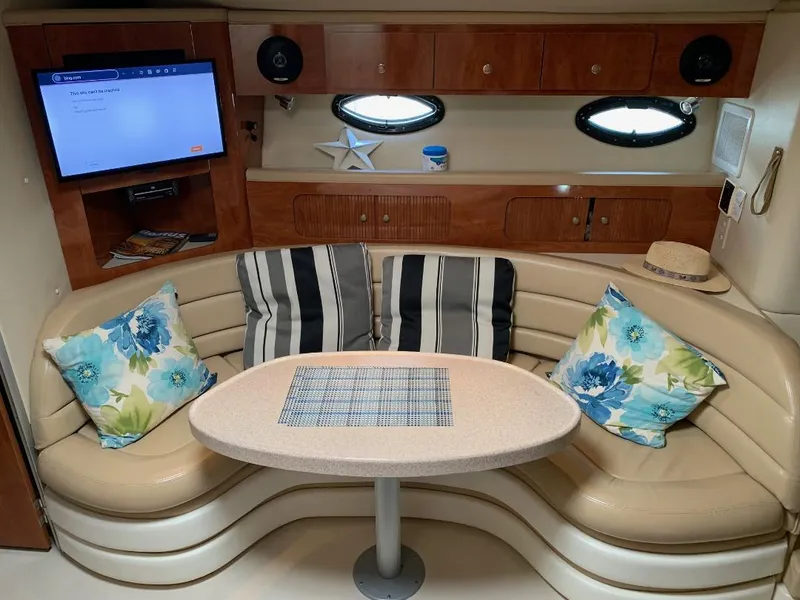 Slide: The Image of 2004 Larson Cabrio 370 interior with cozy seating, floral cushions, and a mounted TV. - 6
