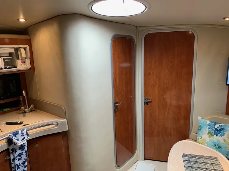 Slide: The Image of Interior of a 2004 Larson Cabrio 370 boat with kitchenette and wooden doors. - 7