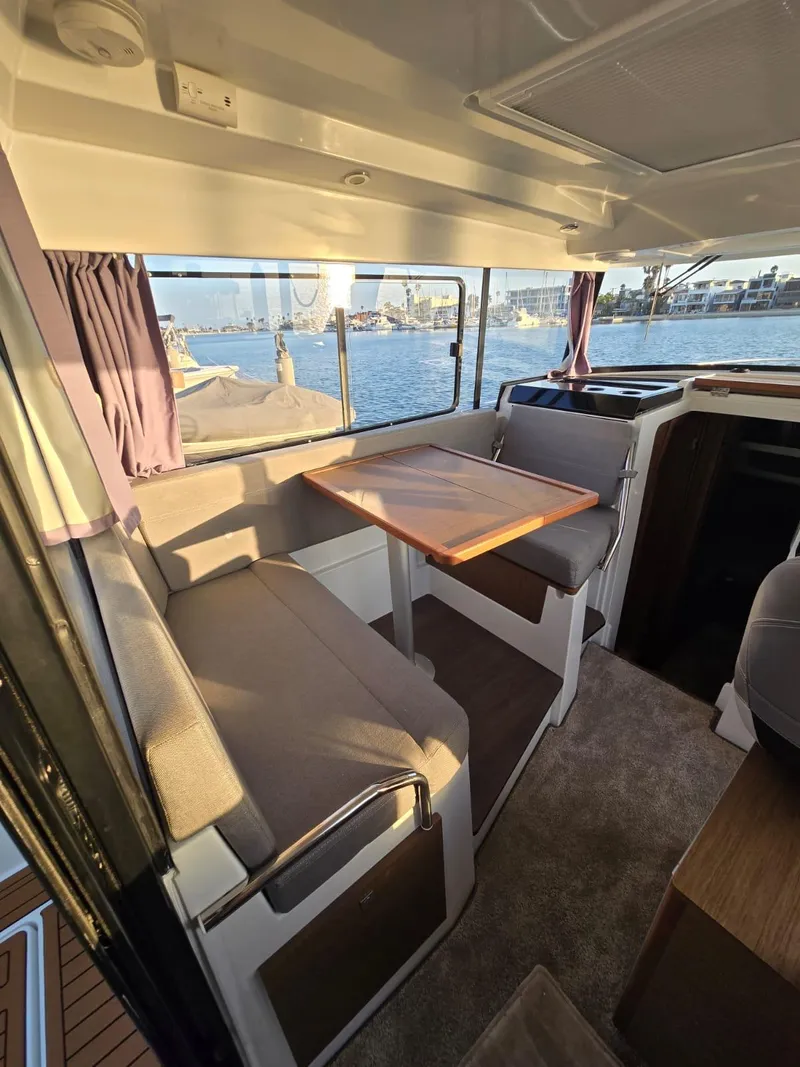 Slide: The Image of 2020 Jeanneau NC 895 Sport interior with seating and table, overlooking water. - 22
