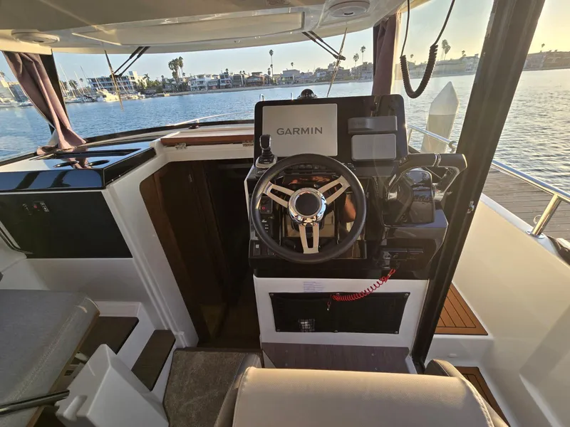 Slide: The Image of 2020 Jeanneau NC 895 Sport helm with Garmin navigation, overlooking serene waterfront. - 24