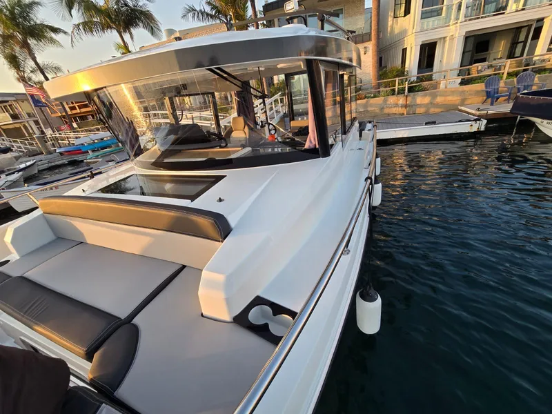 Slide: The Image of 2020 Jeanneau NC 895 Sport boat docked at marina, surrounded by water and palm trees. - 27