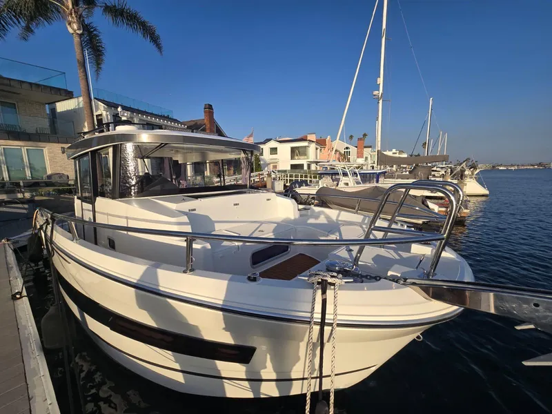Slide: The Image of 2020 Jeanneau NC 895 Sport boat docked at marina, clear sky, waterfront homes in background. - 3